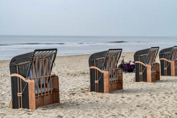 People chill out in the cold beach on the striped sun protective chair background. Seascape cold beach of the North Sea. 