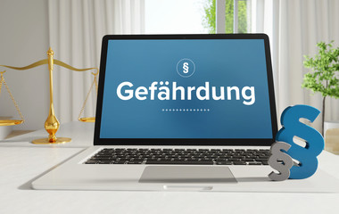 Gefährdung – Recht, Gesetz, Internet. Laptop im Büro mit Begriff auf dem Monitor. Paragraf und Waage. .