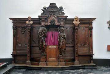 A wooden confessional box with red velvet curtains in the Roman Catholic Church