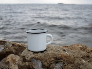 White coffee cup on the rock at sea