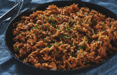 Chicken Breast with Rice and vegetables in a frying pan on dark wooden background