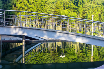 in a city park a metal bridge over a river at dawn.