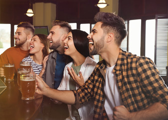 Group of friends watching football in sport bar