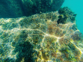 Concrete block under water. Reflection of sun rays under water on a stone.