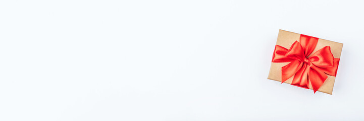 Cardboard gift box with red bow on white background. Flat lay. Top view. Copy space for your text.