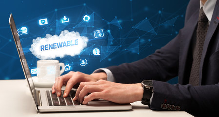 Businessman working on laptop with RENEWABLE inscription, modern technology concept