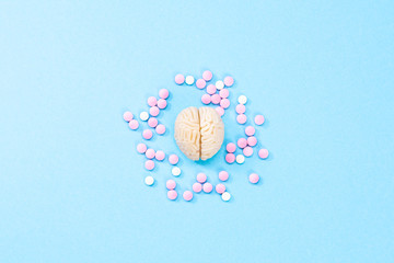 Brain on a blue background with white and pink pills. Some pills for the brain. Symbolical for medicines, psychopharmaceuticals, nootropics and other medicines. Medicine. Brain treatment