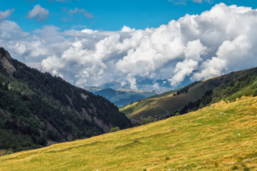 Beautiful early autumn landscape in mountains of Svaneti Georgia with big clouds on a blue sky