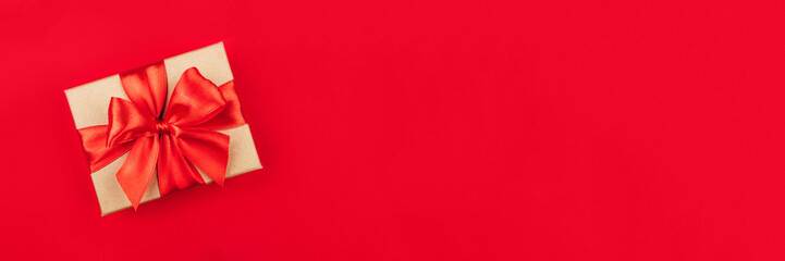 Cardboard gift box with bow on red background. Flat lay. Top view.