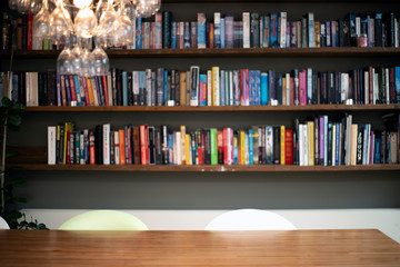 Coloful wall with many books on book shelves in a modern living room blurred, retro interior