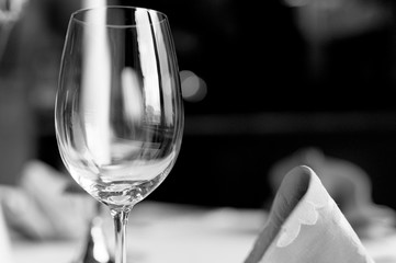 empty wineglass closeup on a background of holiday restaurant. waiting for the holiday. black and white image