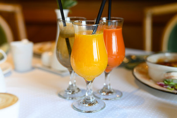 morning Breakfast or brunch in the restaurant. table with drinks and food. a glass of fresh orange juice and a metal drinking straw. selective focus