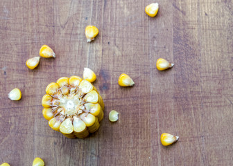 cut corncob and scattered grains on the wooden background