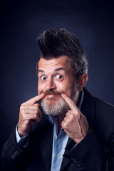 A portrait of funny smiling bearded man with iroquois wearing suit