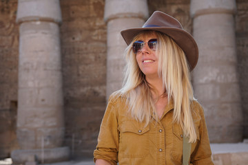 blonde Frau als Tourist in Ägypten vor antiken Säulen. In der Sonnenbrille spiegelt sich ein...