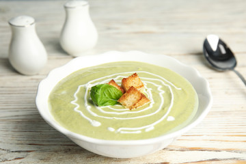 Delicious broccoli cream soup with croutons served on white wooden table