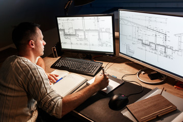 Engineer working at home. He's using a digital pen and examining the blueprint on screen.