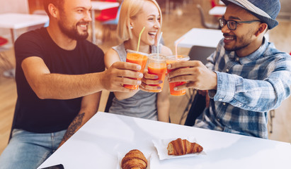 Happy diverse friends clinking cups in cafe