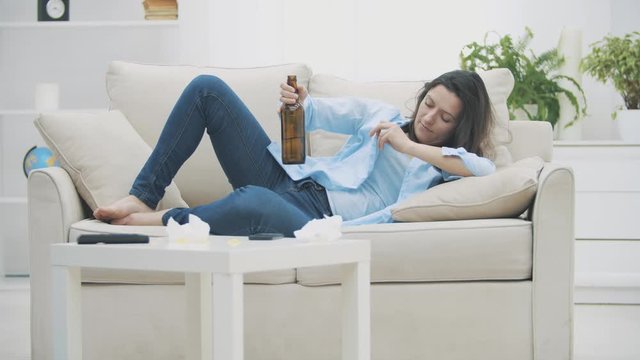 Slowmo. Tipsy brunette woman is holding a bottle of beer and drinking beverage. 4K.