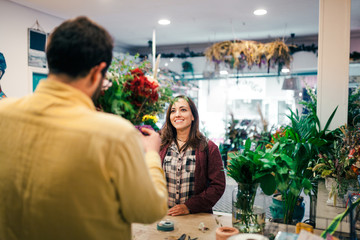 Young woman buying a bouquet of flowers in a florist