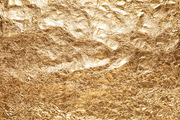 Crumpled gold foil as background, top view
