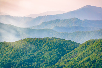 Layers of mountains in the haze during sunset. Beautiful sunset in the hills and mountains. Beautiful sunset in a hilly valley with fog in the lowlands.