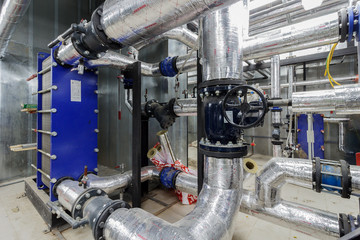 pumping station under construction. pipes of central heating system and water pipes with thermal insulation. Electric motor water pump under repair process at power plant. Industrial zone.