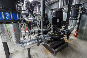 pumping station under construction. pipes of central heating system and water pipes with thermal insulation. Electric motor water pump under repair process at power plant. Industrial zone.