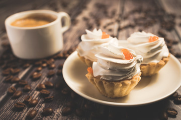 A cup of coffee and cake baskets with brown cream and berry.