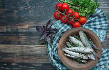 Baltic herring seafood. Salted herring fish in a bowl with spices and herbs. Wood background.