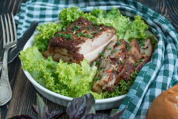 Baked pork belly with spices. Sliced breast served with greens. Traditional dish of Ukraine. Close-up. Space for text.