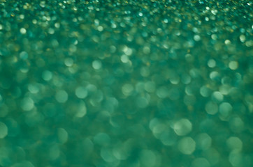 Abstract New Year emerald bokeh background with shining defocus sparkles. Blurred glitters shimmering dust macro close up, copy space for text logo