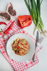 Hot salad with chicken, zucchini and chili pepper, sprinkled with sesame seeds and herbs. Asian food. Light wooden background.