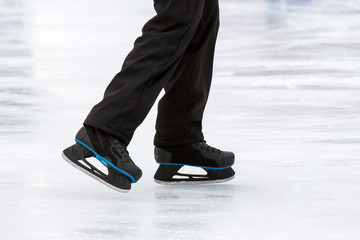 Legs of a man skating on an ice rink. Hobbies and sports. Vacations and winter activities