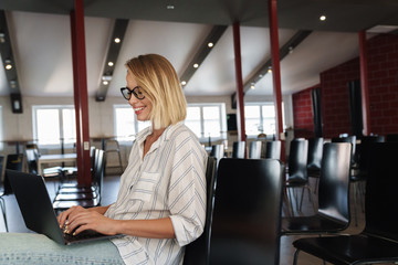 Photo of laughing young woman working on laptop and cellphone