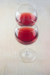 glasses with red wine standing next to each other on a light wooden background