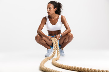 Portrait of african american woman doing exercises with batting ropes