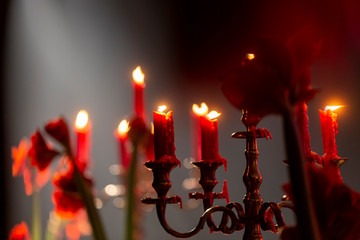 Banquet table with red candles, bronze color candlesticks and red flowers (amarilli).
