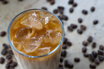 Detail of a Glass of iced coffee with milk, cream with beans in the background