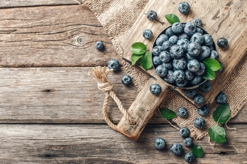 Freshly picked blueberries in bowl on wooden background. Healthy eating and nutrition.