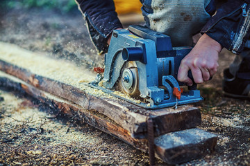 Circular saw for cutting boards into the hands of the builder, the man sawed bars, construction and home renovation, repair and construction tool. Carpenter Using Circular Saw for wood. Close-up