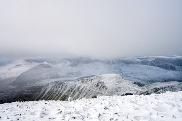 Snowy mountain peaks in Rondane national park in Norway. Snowy, foggy and frozen landscape during winter. Hiking and nature concept.