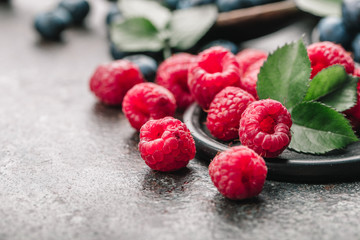 Freshly picked raspberries in bowl on old metal background. Healthy eating and nutrition.