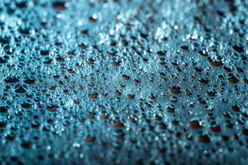 Shiny drops of water on a blue background, abstract rainy wallpaper