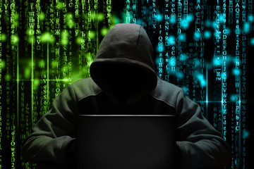a computer hacker breaks a password while sitting in a dark room at a laptop. Cyber security