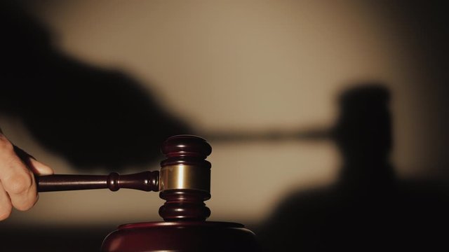 Close - up of the judge knocking three times with a wooden mallet.