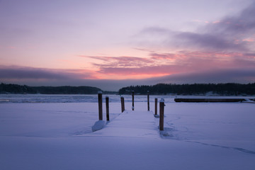 Snow covered pier at sunset. Turku, Finland.