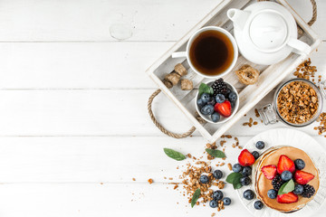 Obraz na płótnie Canvas Healthy breakfast with american pancake, granola, fruits, berries on white background.