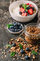 Healthy breakfast with granola, yogurt, fruits, berries on dark metal background. Summer homemade breakfast.