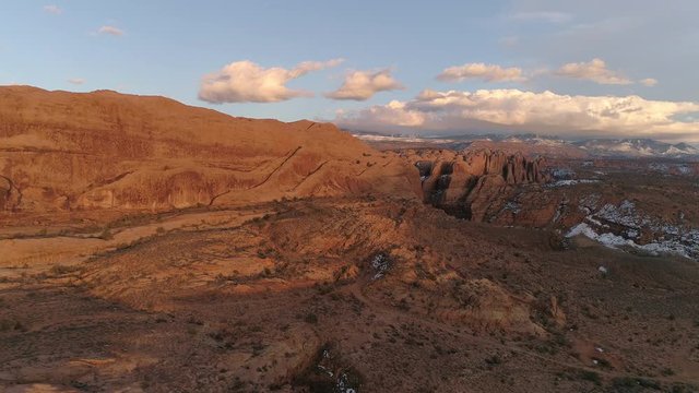 Flying towards red rock wall in the Moab desert at sunset viewing the La Sal mountains.